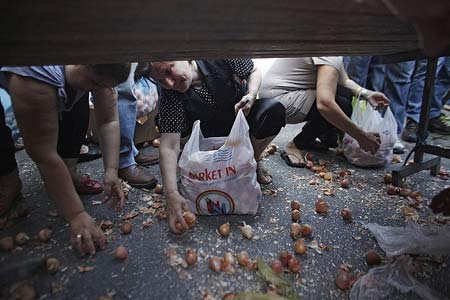   شهروندان یونانی در حال جمع اوری پیاز از کف خیابان در جریان اعتصاب فروشندگان خیابانی- آتن