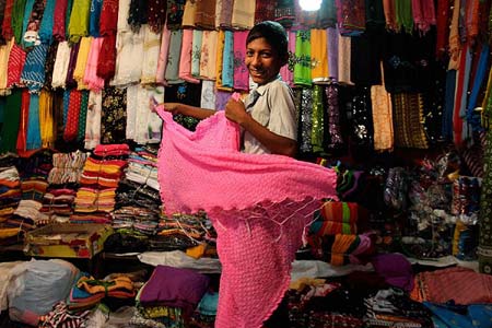 روسری فروش جوان  اجناس جدید خود را برای فروش بیشتر در روز عید فطر آماده می کند- کلکته، هند