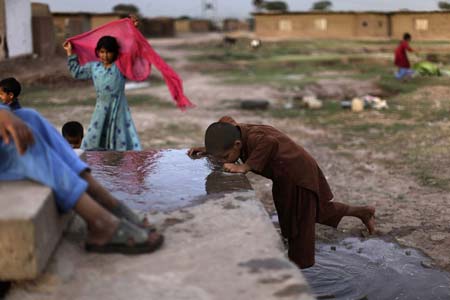 نوجوان تشنه پاکستانی در حال نوشیدن آب شیرین در حال ریختن بر روی زمین در یک اردوگاه آوارگان در حومه شهر اسلام آباد